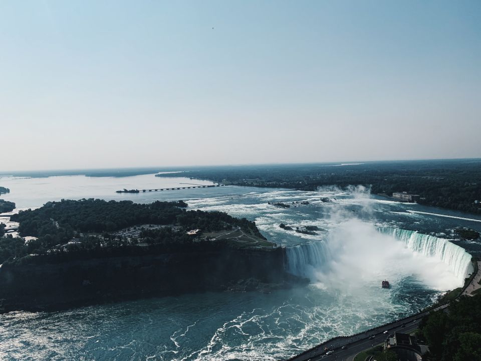 An aerial view of the Horseshoe Falls and the Niagara River under a clear sky.