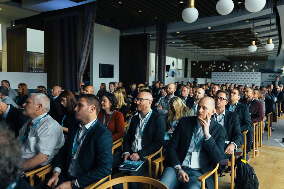 A large audience seated in a wide conference hall.