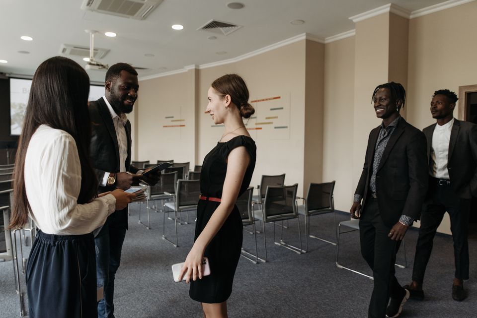 Attendees stand and talk in a conference room.